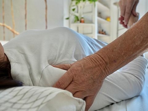 Una mujer está acostada en una cama recibiendo un masaje de una persona.