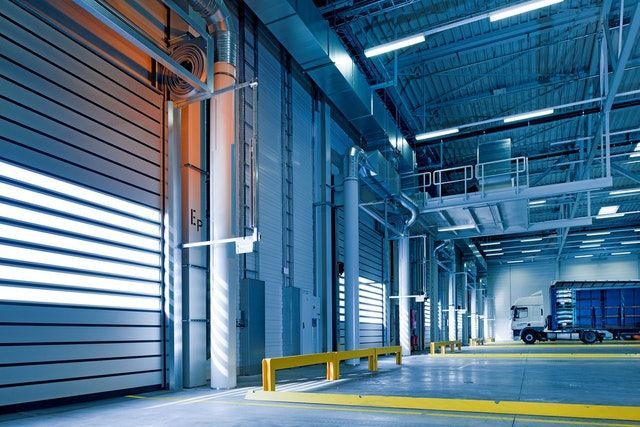 Entrepôt industriel vide avec portes de quai de chargement bleues et garde-corps de sécurité jaunes