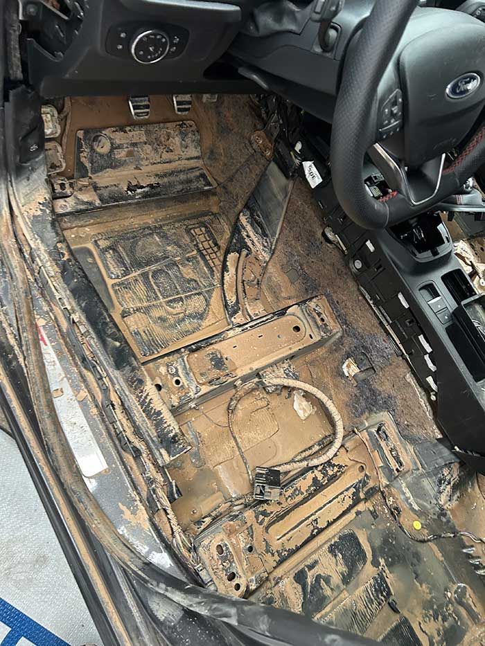 El interior de un coche sucio con volante y tablero.