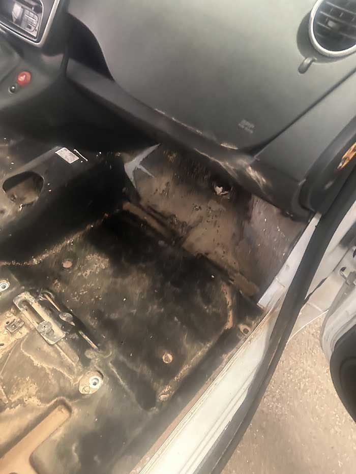 El interior de un coche con el suelo y el salpicadero sucios.