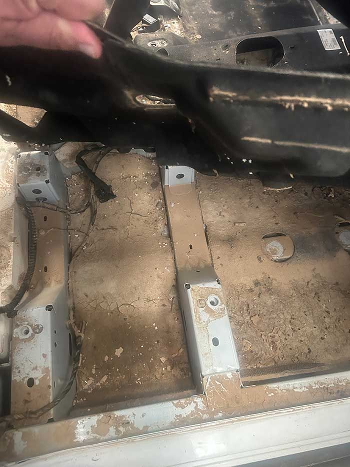 Una persona sostiene un trozo de metal en el maletero de un coche.