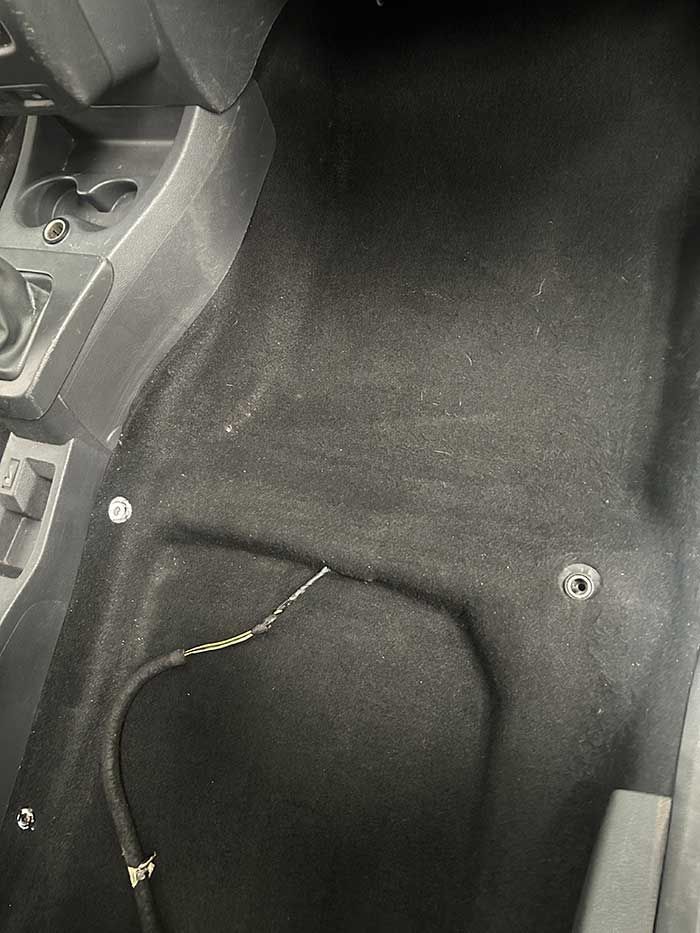 Un piso de automóvil negro con una manguera saliendo de él.