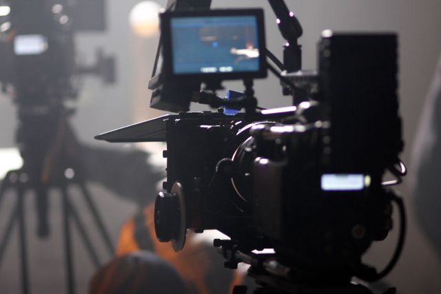 Eine professionelle digitale Kinokamera auf einem Stativ, die während einer Filmproduktion auf eine Szene gerichtet ist.
