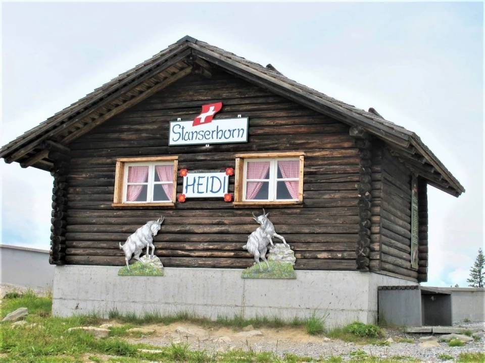 Eine rustikale Blockhütte auf dem Stanserhorn mit einer Schweizer Flagge, einem „HEIDI“-Schild und zwei Ziegenfiguren an der Holzwand.