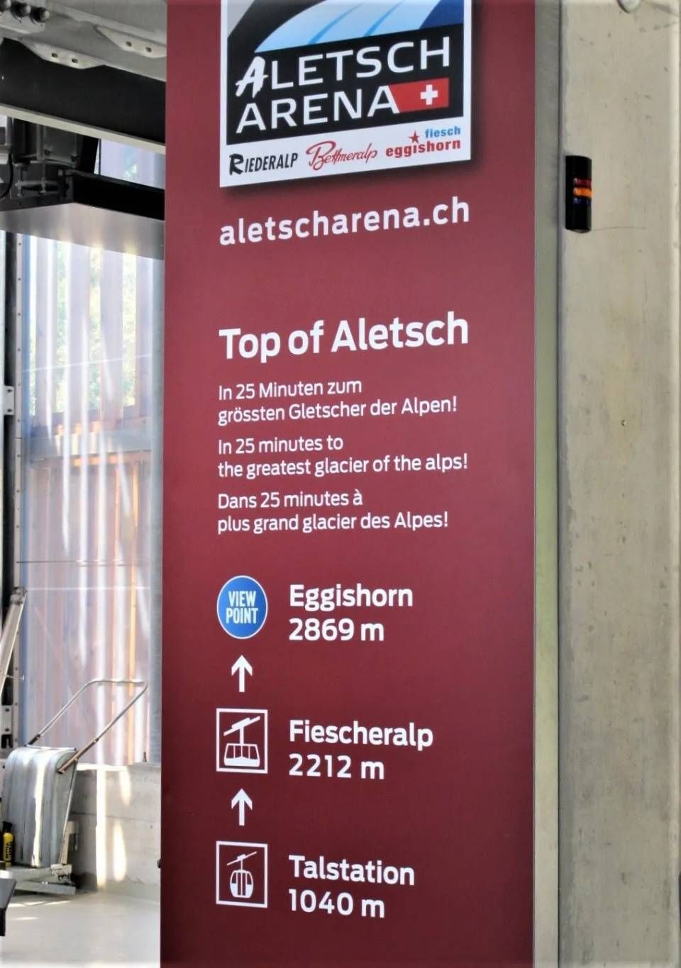 Ein senkrechtes, kastanienbraunes Schild in der Aletsch Arena zeigt Richtungsangaben und Höhenangaben für das Eggishorn, die Fiescheralp und das Tal an.