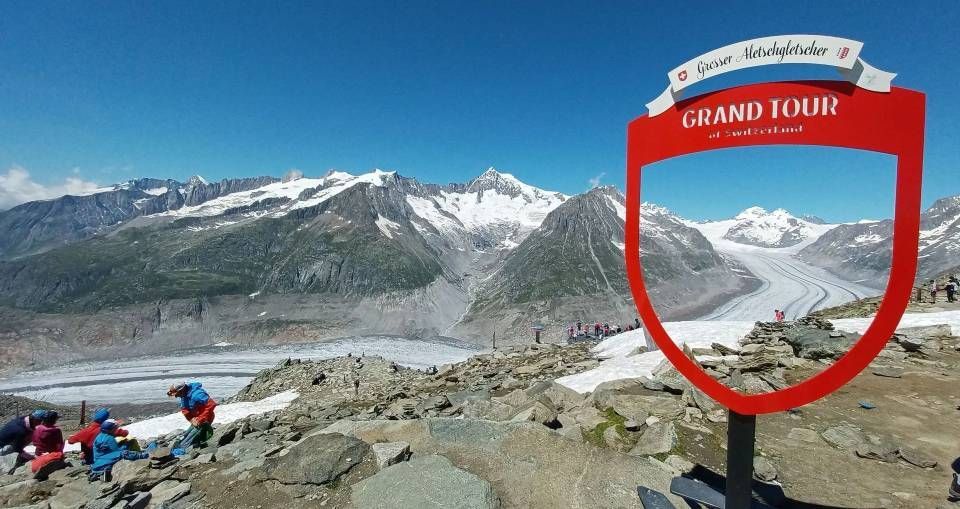 Ein leuchtend roter Bilderrahmen der Grand Tour of Switzerland, der den Aletschgletscher in den schneebedeckten Schweizer Alpen einrahmt.