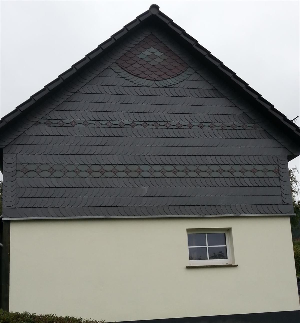 Ein weißes Haus mit einem schwarzen Dach und einem Fenster