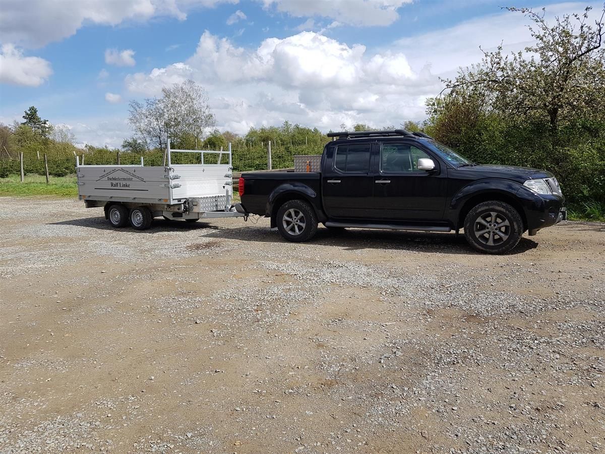 Ein schwarzer Lastwagen zieht auf einem Schotterplatz einen Anhänger.