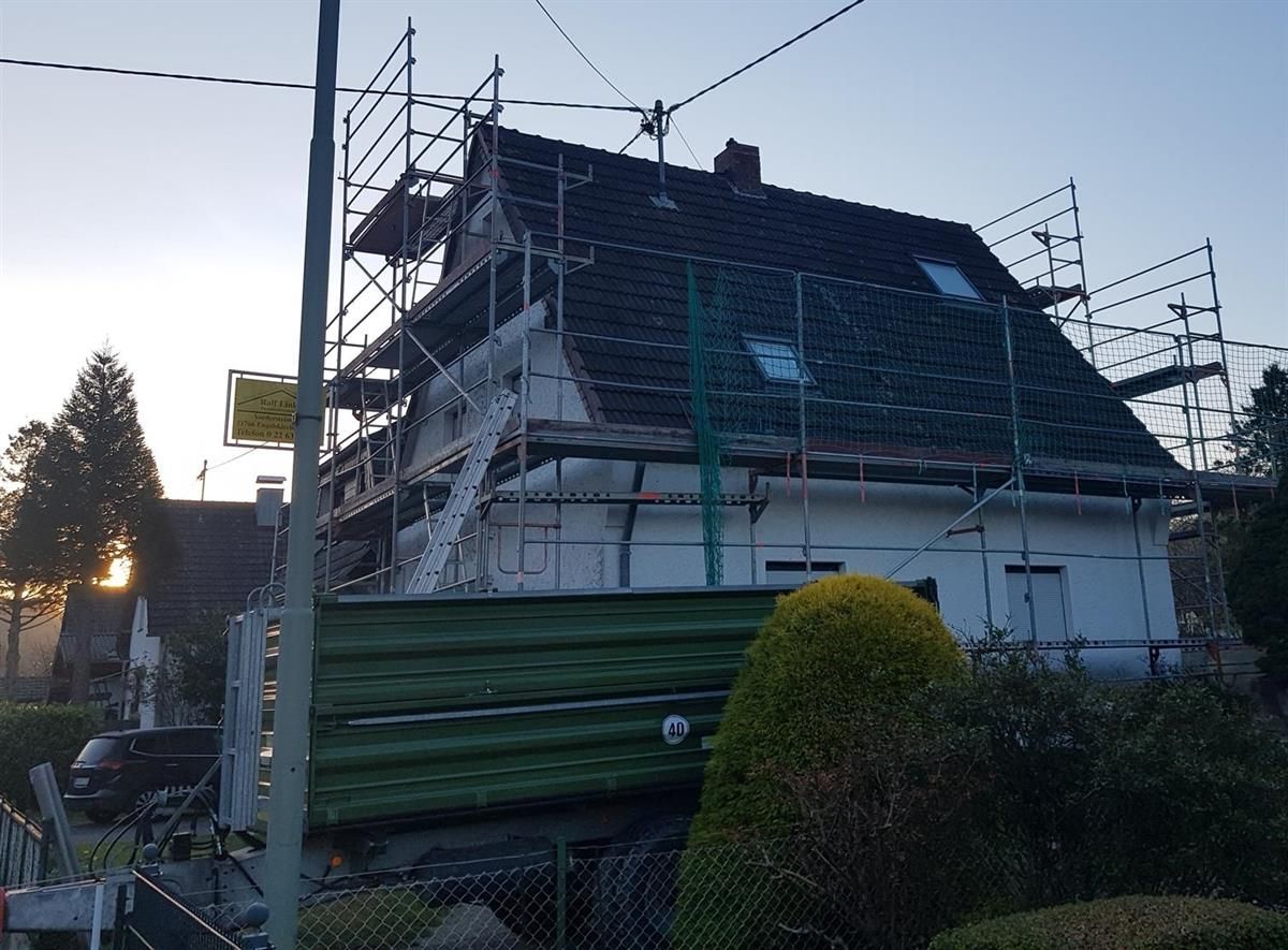 Es wird ein Haus mit Gerüst auf dem Dach gebaut.
