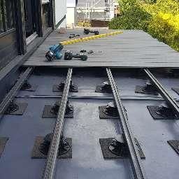 Auf einem Betonboden wird ein Holzdeck errichtet.