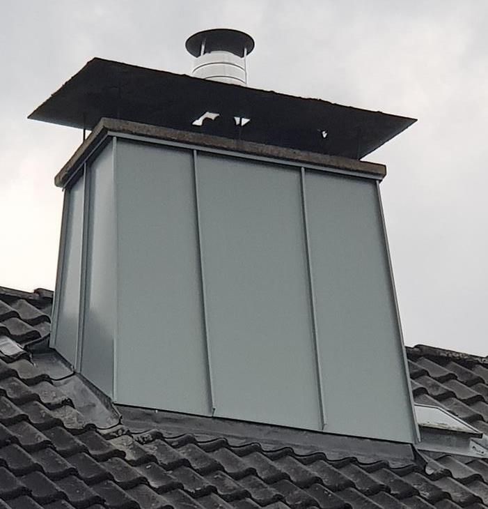 Auf einem Ziegeldach sitzt ein Schornstein.