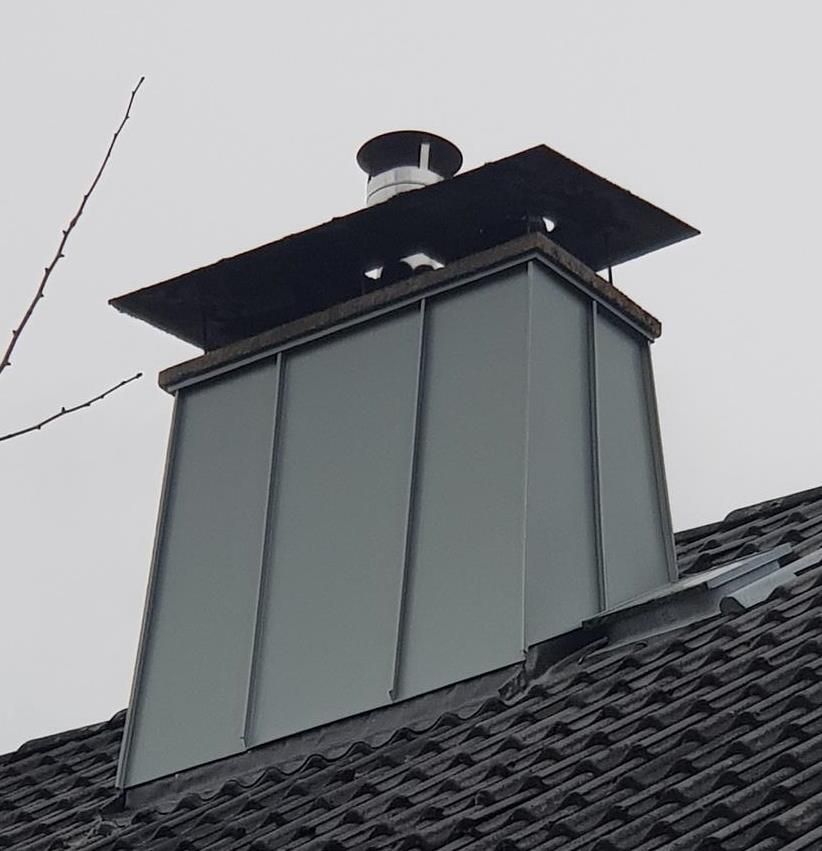 Ein Schornstein auf einem schwarzen Ziegeldach