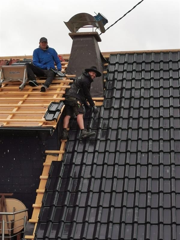 Zwei Männer arbeiten auf dem Dach eines Gebäudes