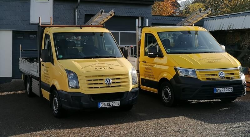 Zwei gelbe Lieferwagen parken vor einem Gebäude.