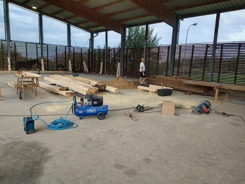 In einem Gebäude steht ein blauer Luftkompressor auf dem Boden.