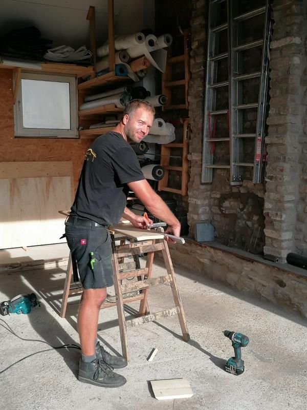 Ein Mann arbeitet in einer Garage an einem Stück Holz.