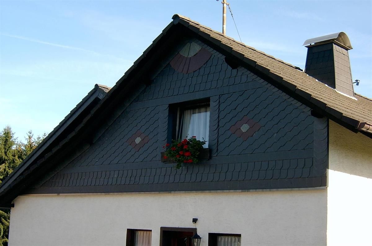 Ein weißes Haus mit einem schwarzen Dach und einem Fenster mit Blumen darin