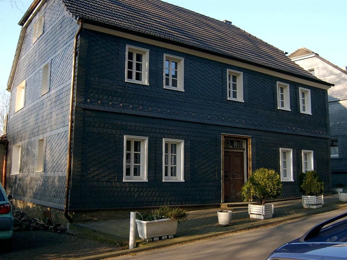 Ein großes Haus mit vielen Fenstern und einem davor geparkten Auto