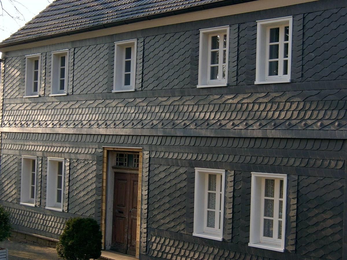 Ein graues Gebäude mit weißen Fenstern und Fensterläden