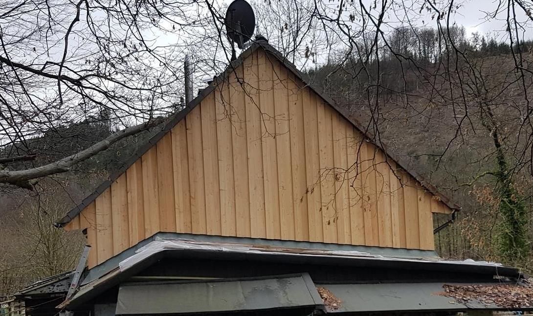 Ein Holzhaus mit Metalldach ist von Bäumen umgeben.