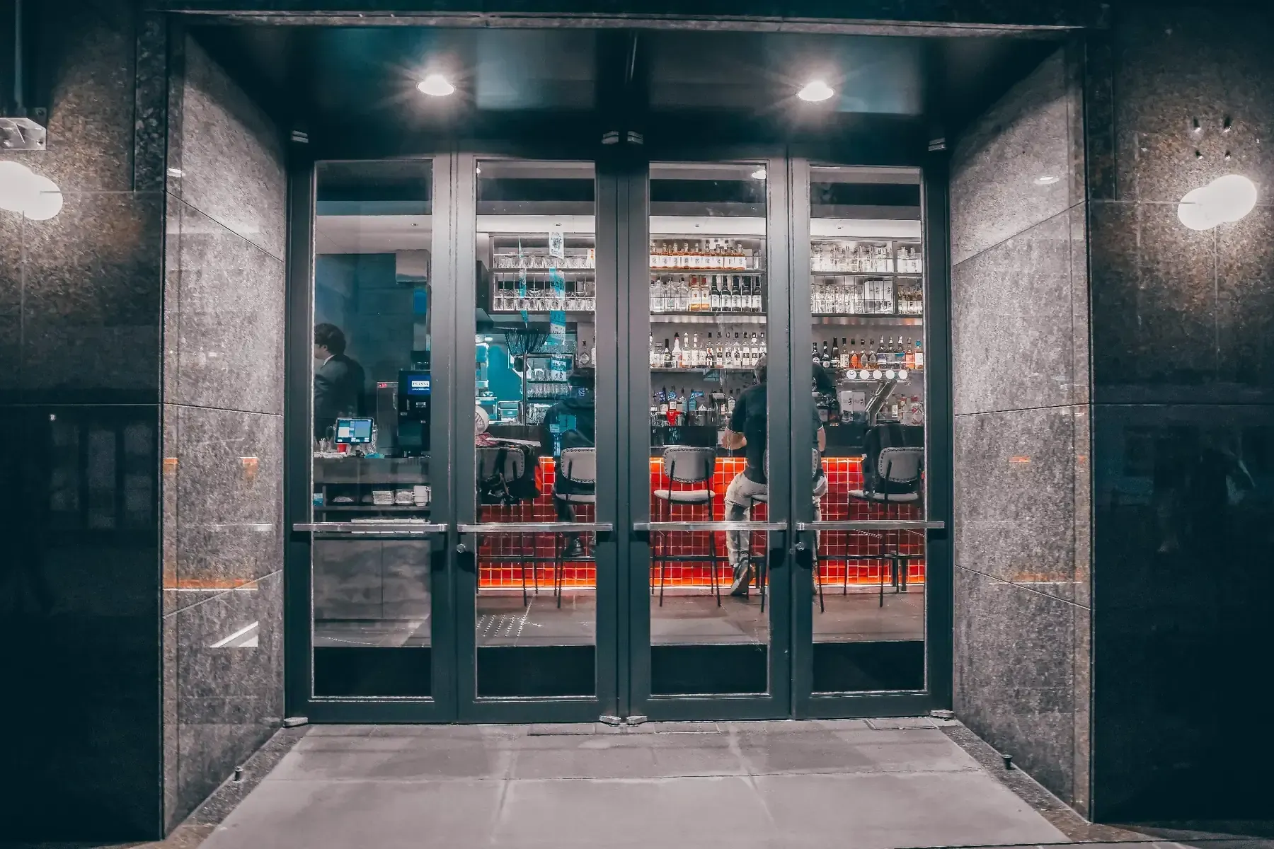 Entrada del restaurante con fachada de cristal y sillas rojas visibles en el interio.
