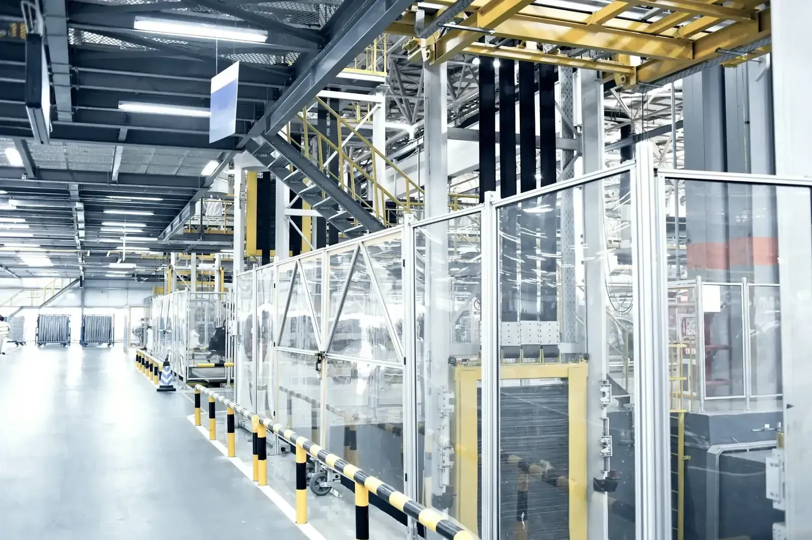 Línea de producción automatizada con claras barreras de seguridad y maquinaria en un luminoso almacén industrial.