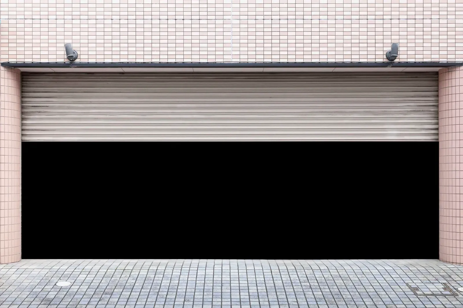 Puerta de garaje metálica enrollable cerrada en la fachada de un edificio de ladrillo.
