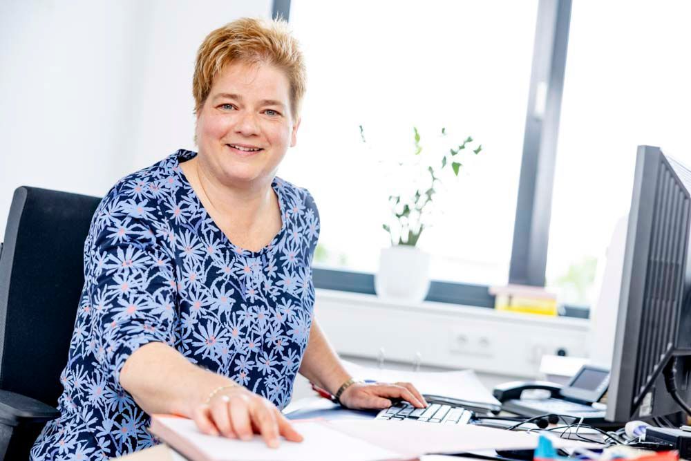 Eine Frau sitzt an einem Schreibtisch vor einem Computer.