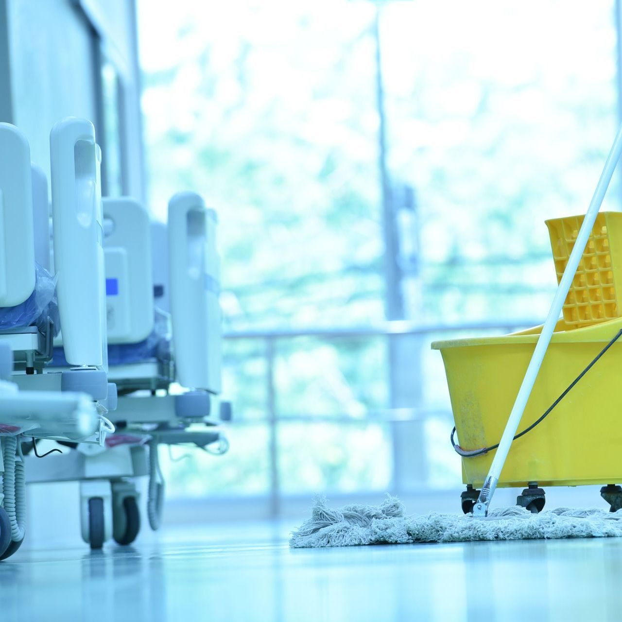 Un chariot de nettoyage jaune devant un lit d'hôpital