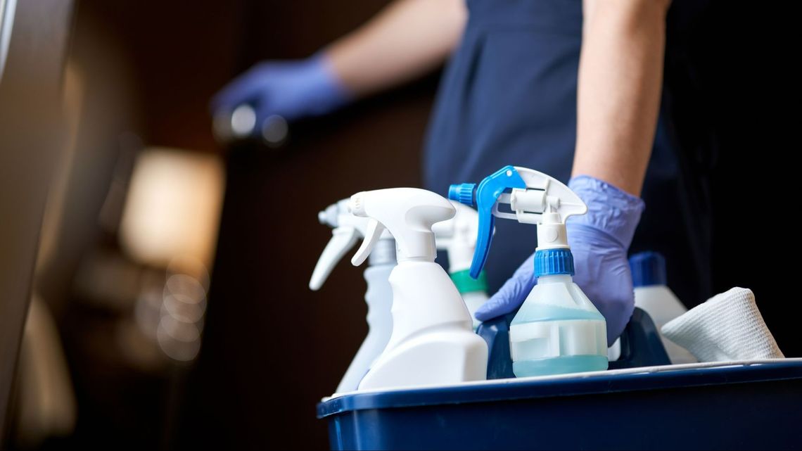 Homme avec des gants portant un seau de produits ménagers