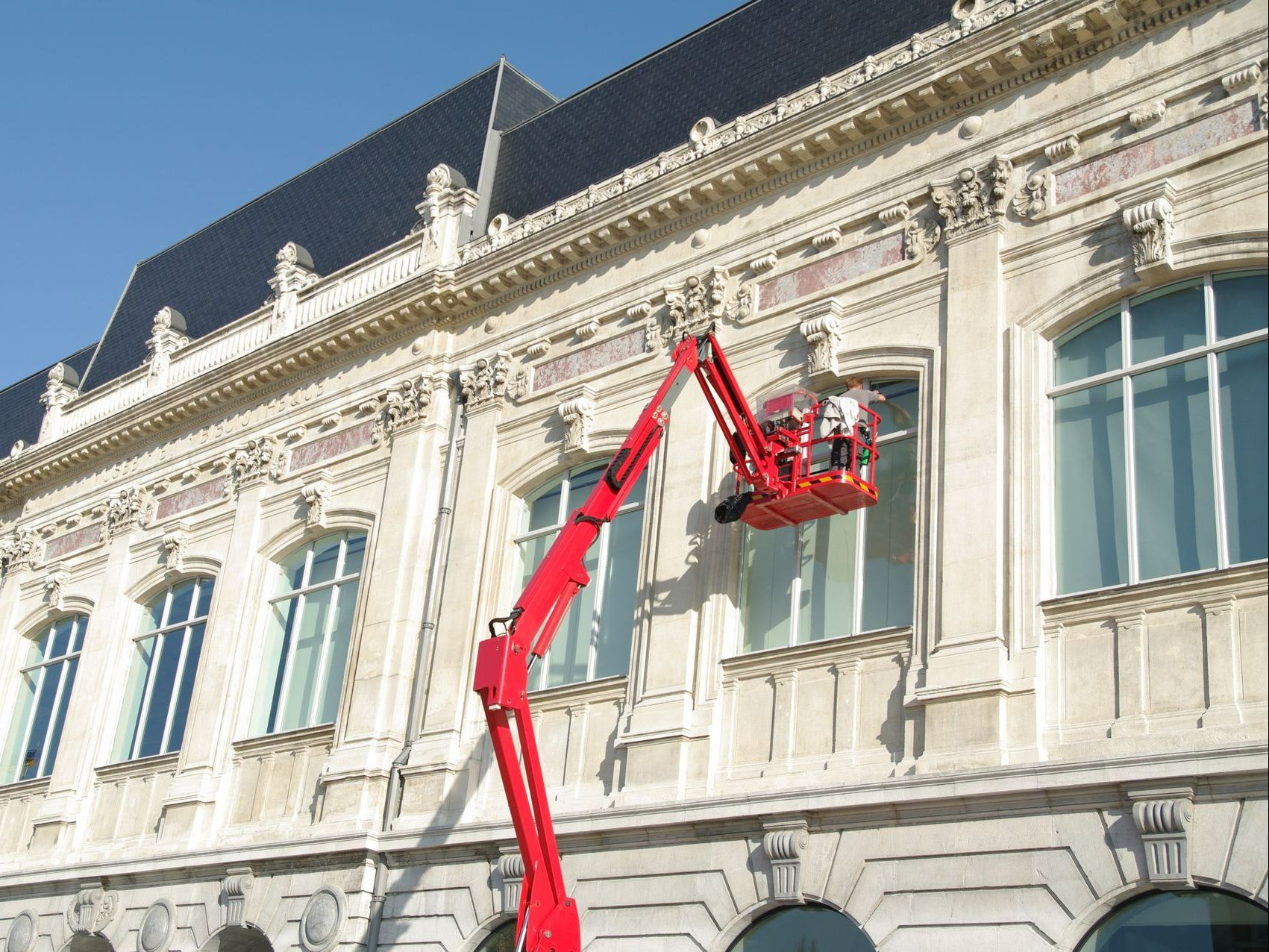 Nettoyage d'une grande fenêtre en hauteur à l'aide d'une nacelle