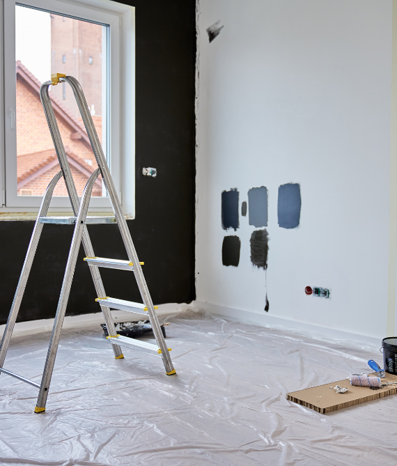 Une pièce en cours de peinture ; une échelle se dresse devant une fenêtre.