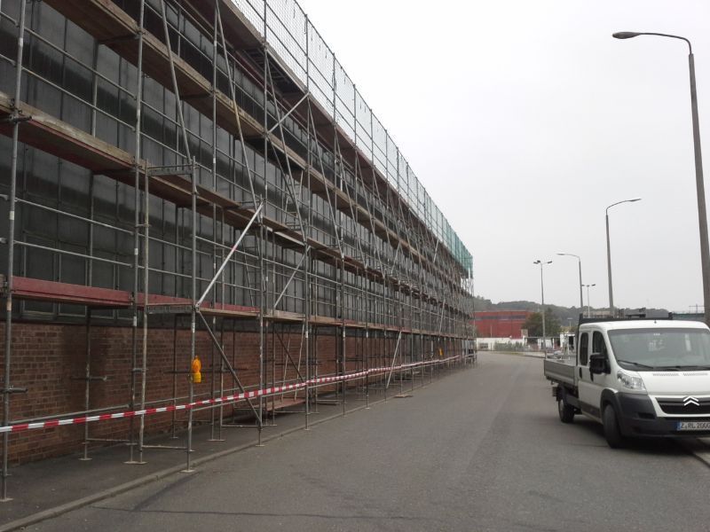 Gerüst an einem Gebäude, daneben parkt ein Pickup