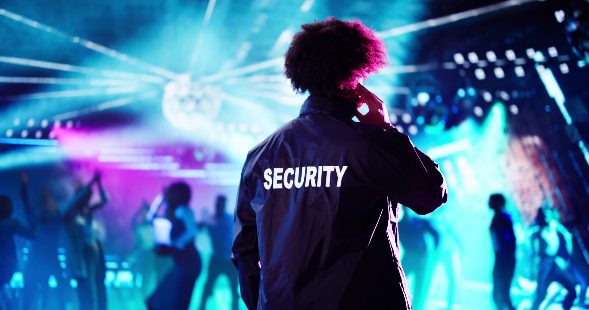Guardia de seguridad en un club, de espaldas a la cámara, hablando por teléfono.
