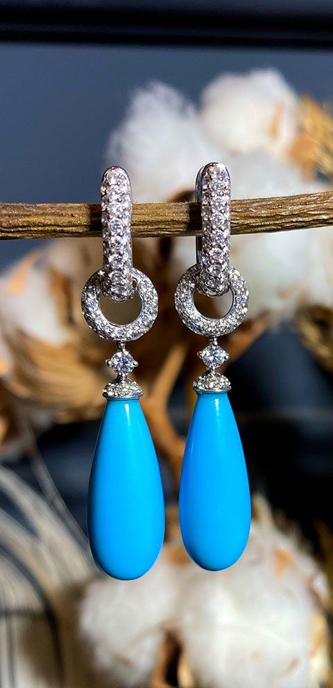 Boucles d'oreilles en forme de larme turquoise avec des accents de diamants suspendues à une brindille.