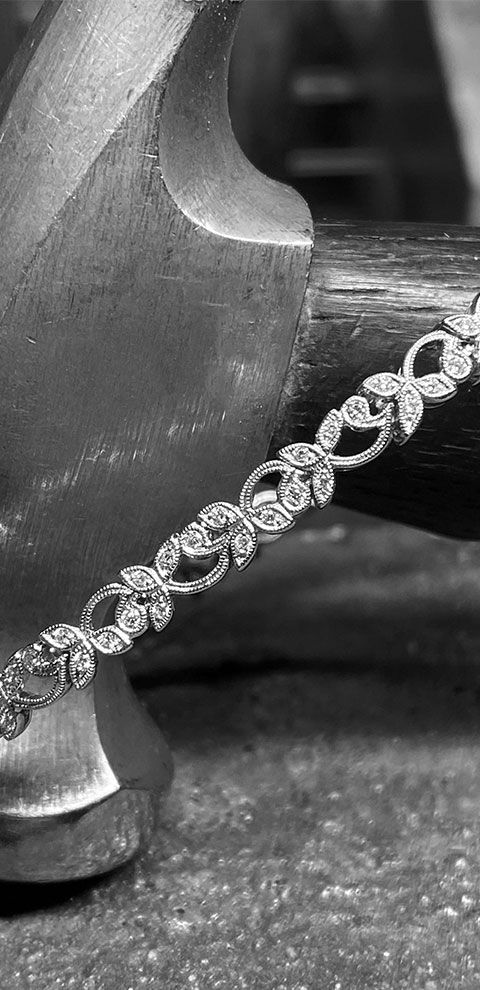 Bracelet en diamant sur une surface sombre, reposant partiellement sur un objet métallique, potentiellement un outil.