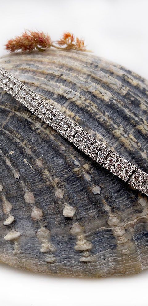 Bracelet en diamant reposant sur un coquillage texturé gris foncé.