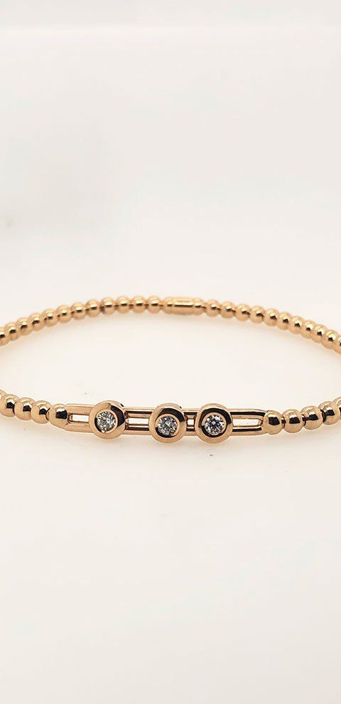 Bracelet en or rose avec trois diamants sur fond blanc.