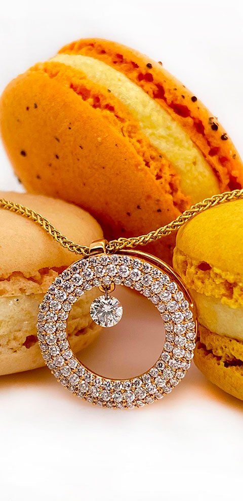 Collier en or avec pendentif diamant, entouré de macarons, sur fond blanc.