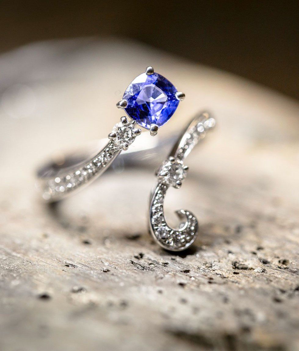 Bague en diamant avec une grosse pierre précieuse bleue sur une surface en bois.