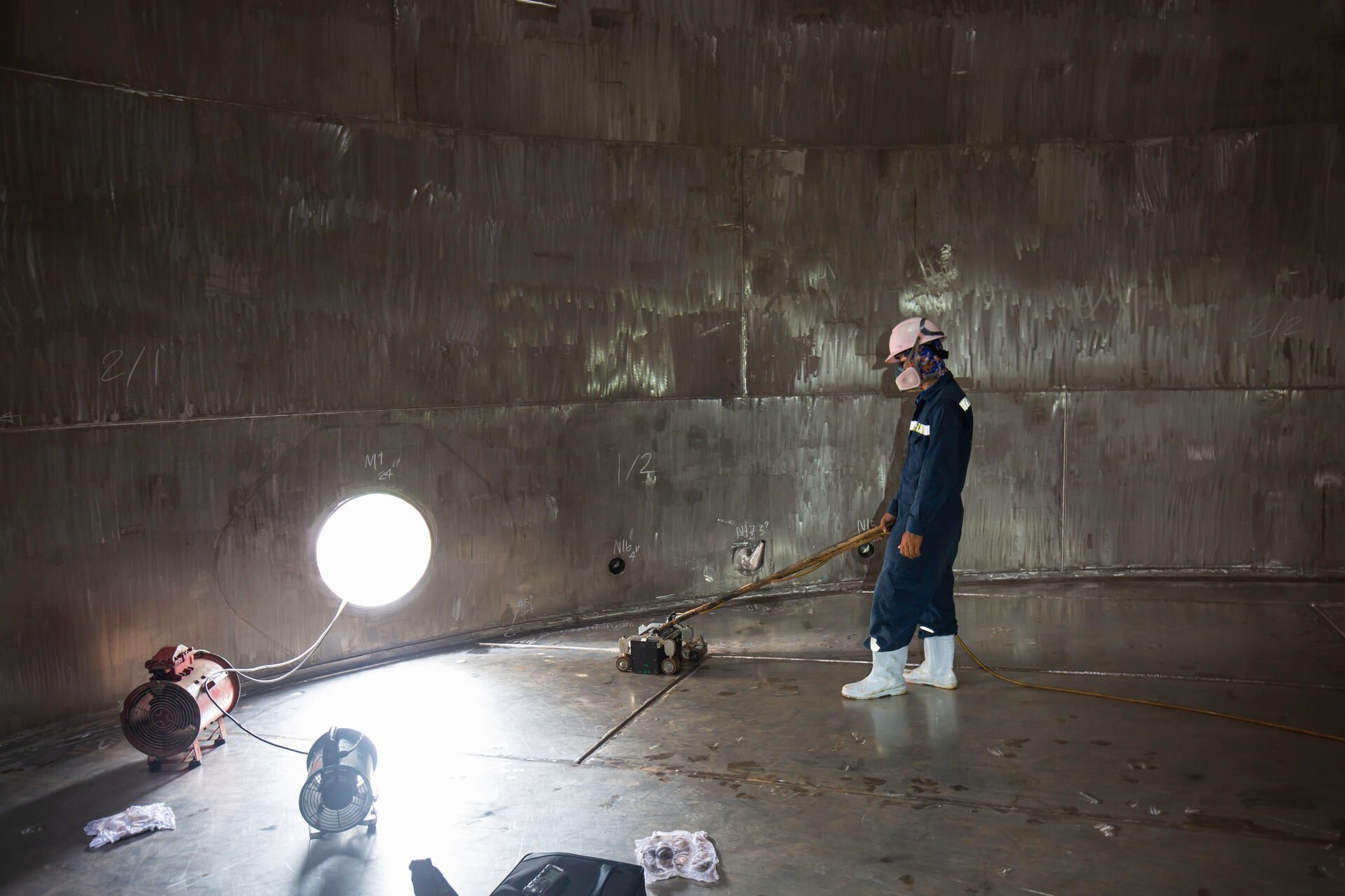 Ein Mann mit Schutzhelm steht in einem großen Raum, 