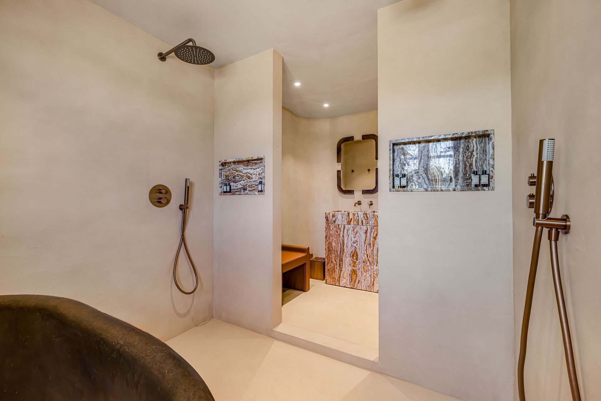 Bedroom with open door to a balcony, bed with patterned pillows and headboard, decorative wall lights.