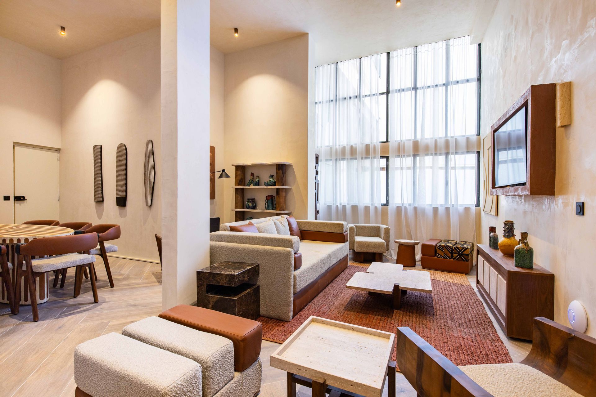 Living room with neutral colors, furniture, a large window, and decorative art.