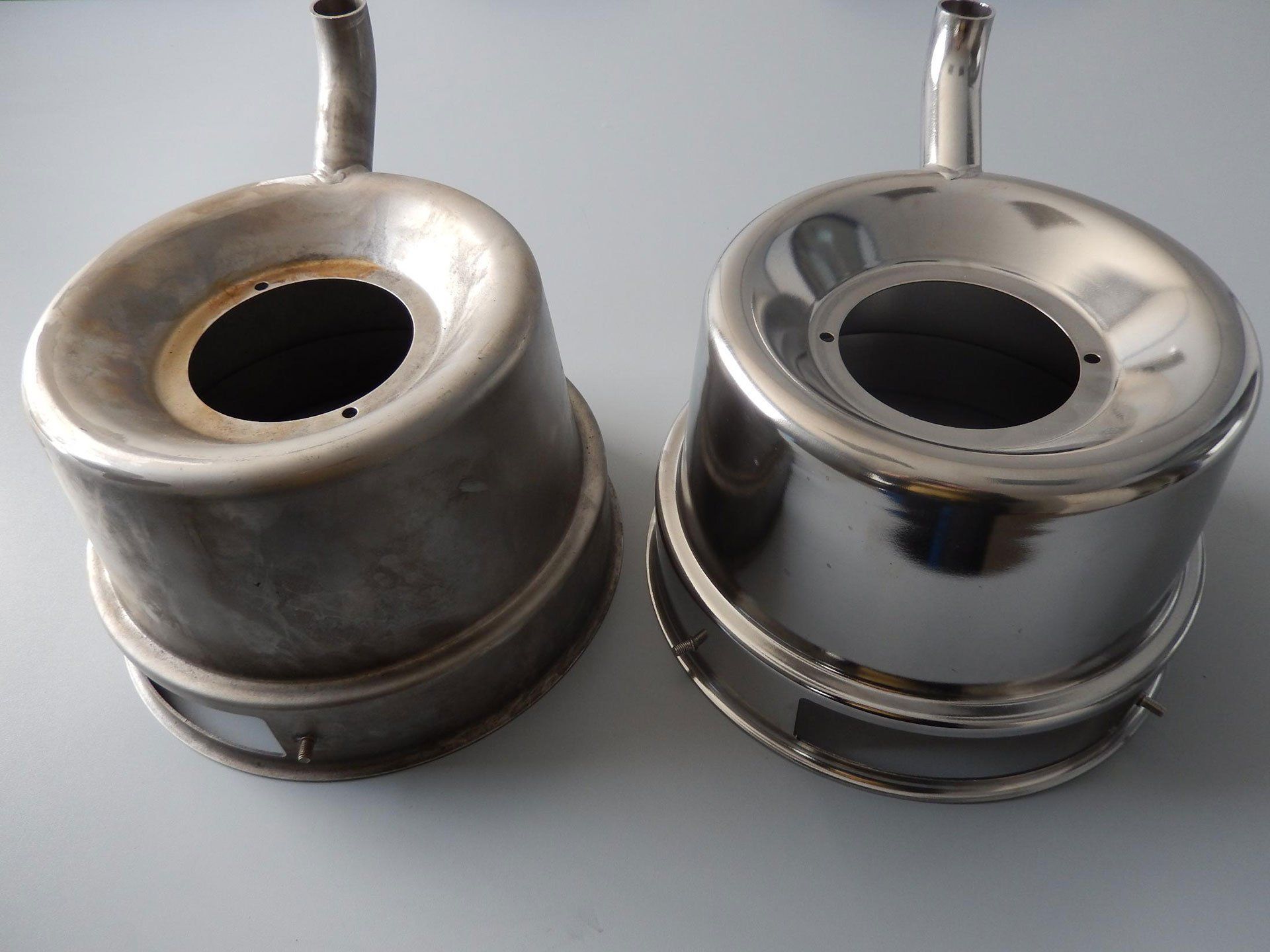Deux pièces métalliques de moteur, l'une mate, l'autre polie, avec des ouvertures circulaires et des tubes fixés.