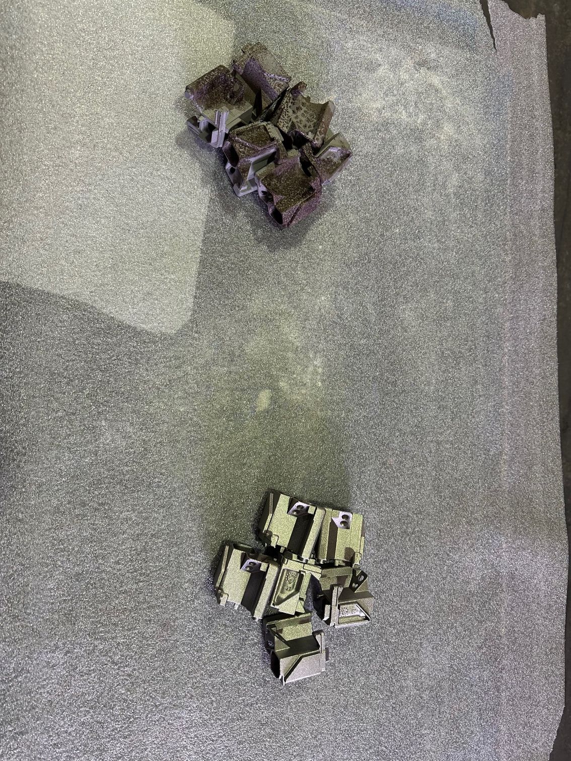 Deux piles d'objets métalliques cubiques sur une surface grise texturée.