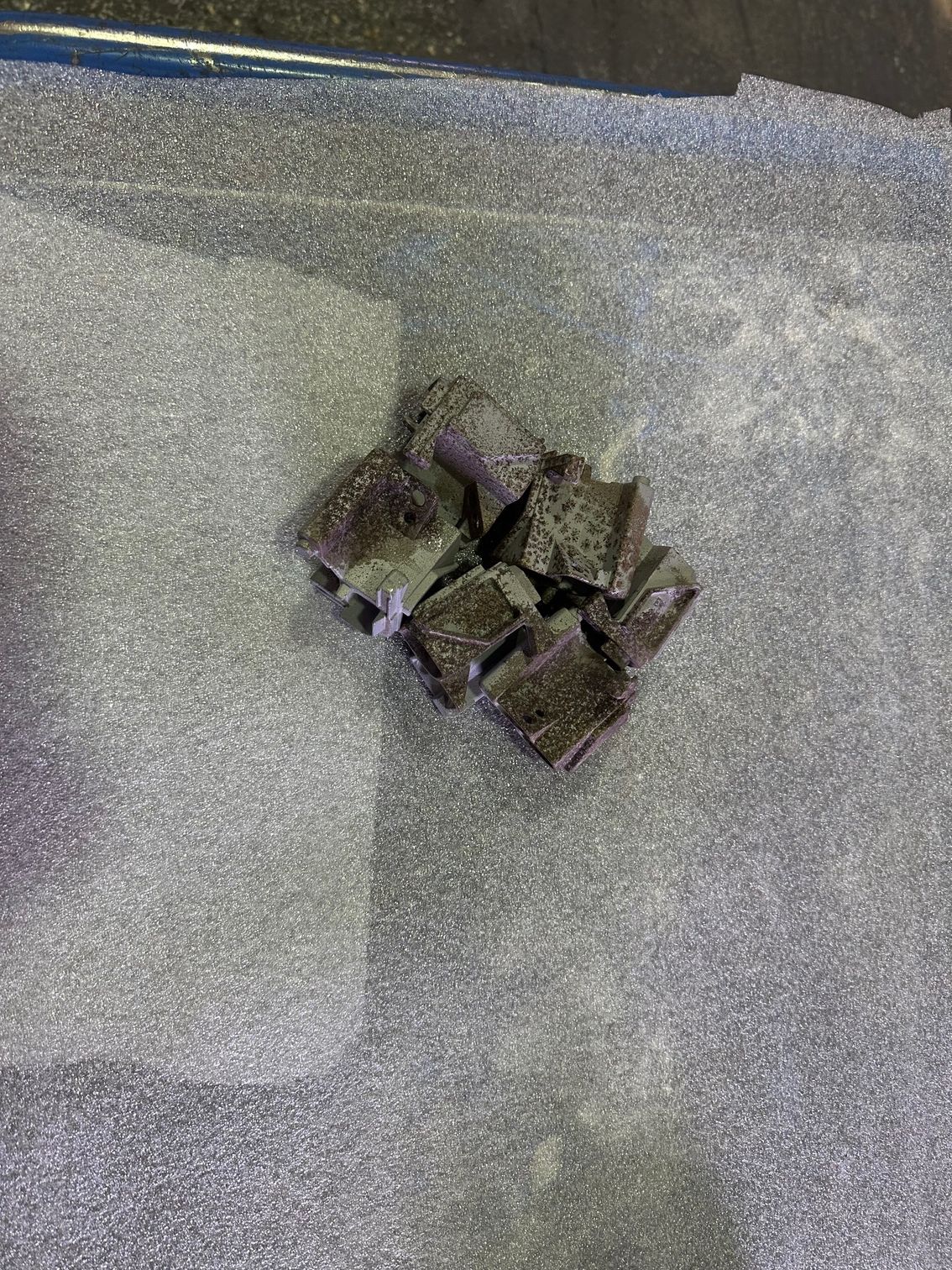 Petit tas d'objets cubiques sombres sur une surface grise texturée.