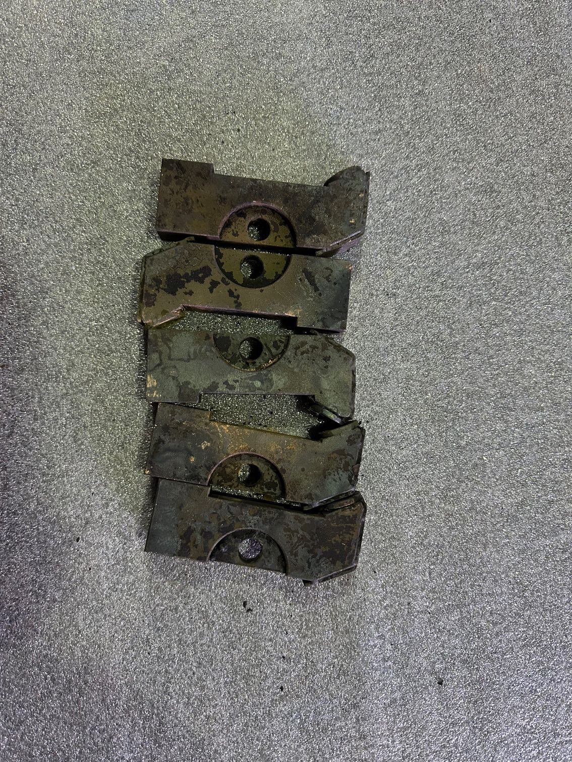 Pile de six morceaux de métal cassés présentant des trous circulaires.