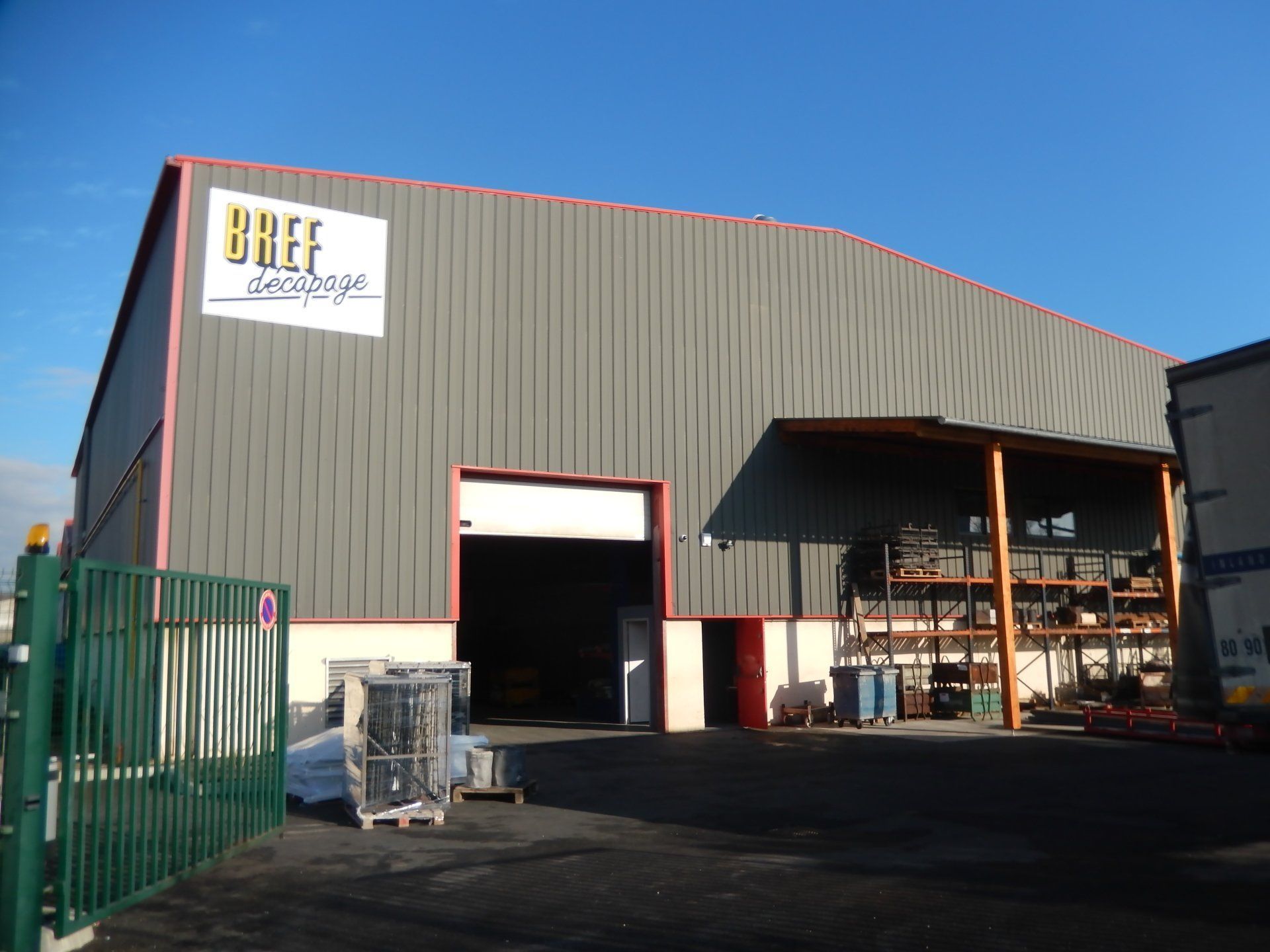 Une grande plaque de métal gris foncé et réfléchissante, posée sur une palette en bois à l'extérieur.