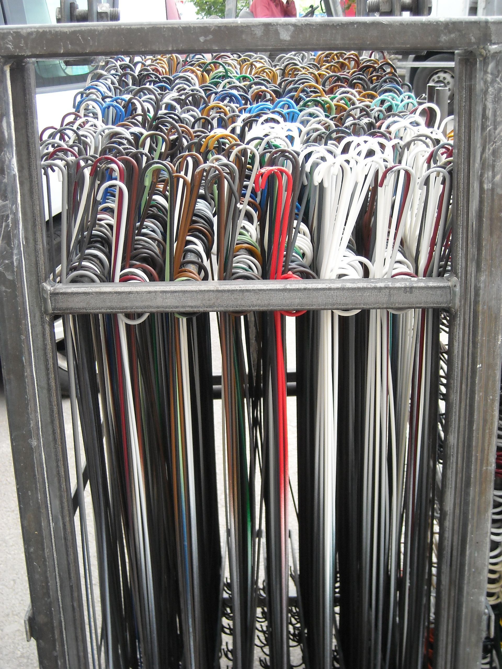 Un chariot métallique rempli de cannes de couleurs variées, avec des poignées et des fûts différents.