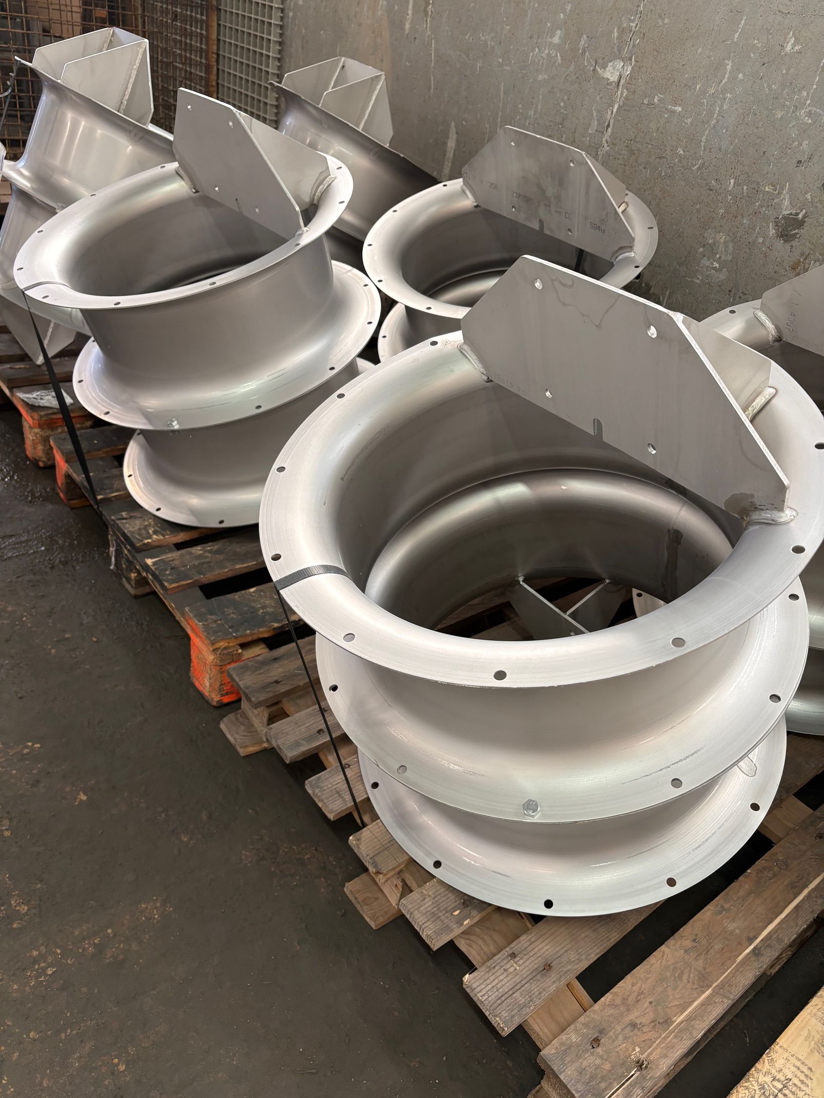 Trois tuyaux sales dans une rigole en béton sombre, sous un ciel d'un bleu éclatant.